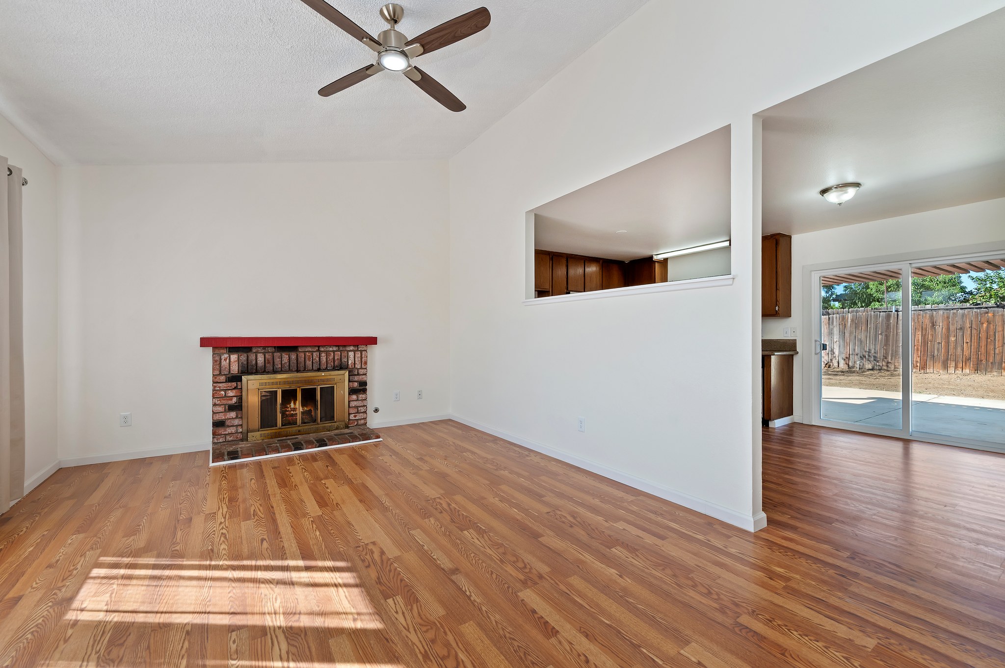 Living room with brick fireplace and wood-look flooring | 14927 Wintergreen St, Moreno Valley